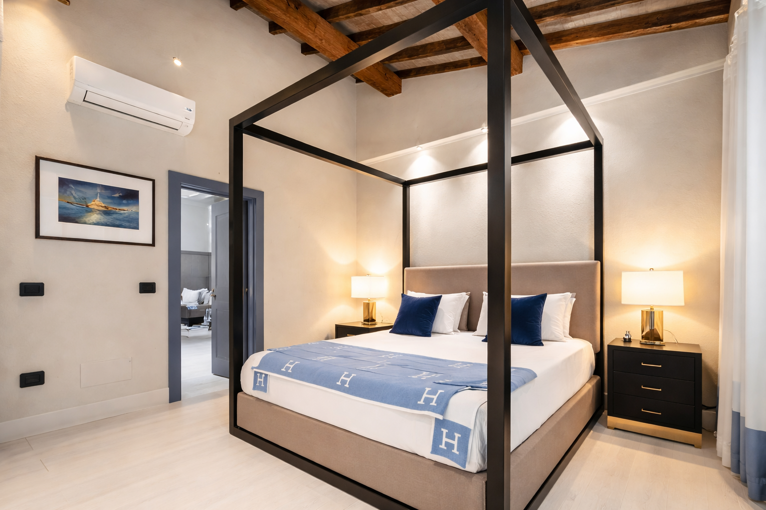 Master bedroom with a four-poster bed, exposed beams, and blue accent cushions